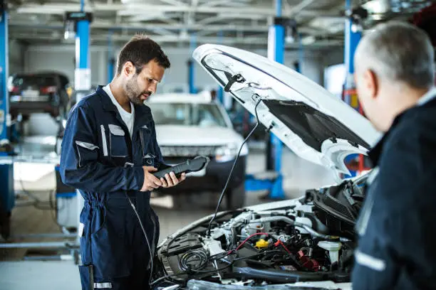 auto-mechanic-working-with-car-diagnostic-tool-in-a-repair-shop